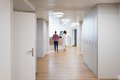Fachärztin und Hebamme stehen am Ende des leeren Flures am Empfangsdesk der Geburtsklinik in Basel. Moderne atmösphäre und saubere, renovierte Räumlichkeiten stellvertretend für ein sicheres gebären in Basel 